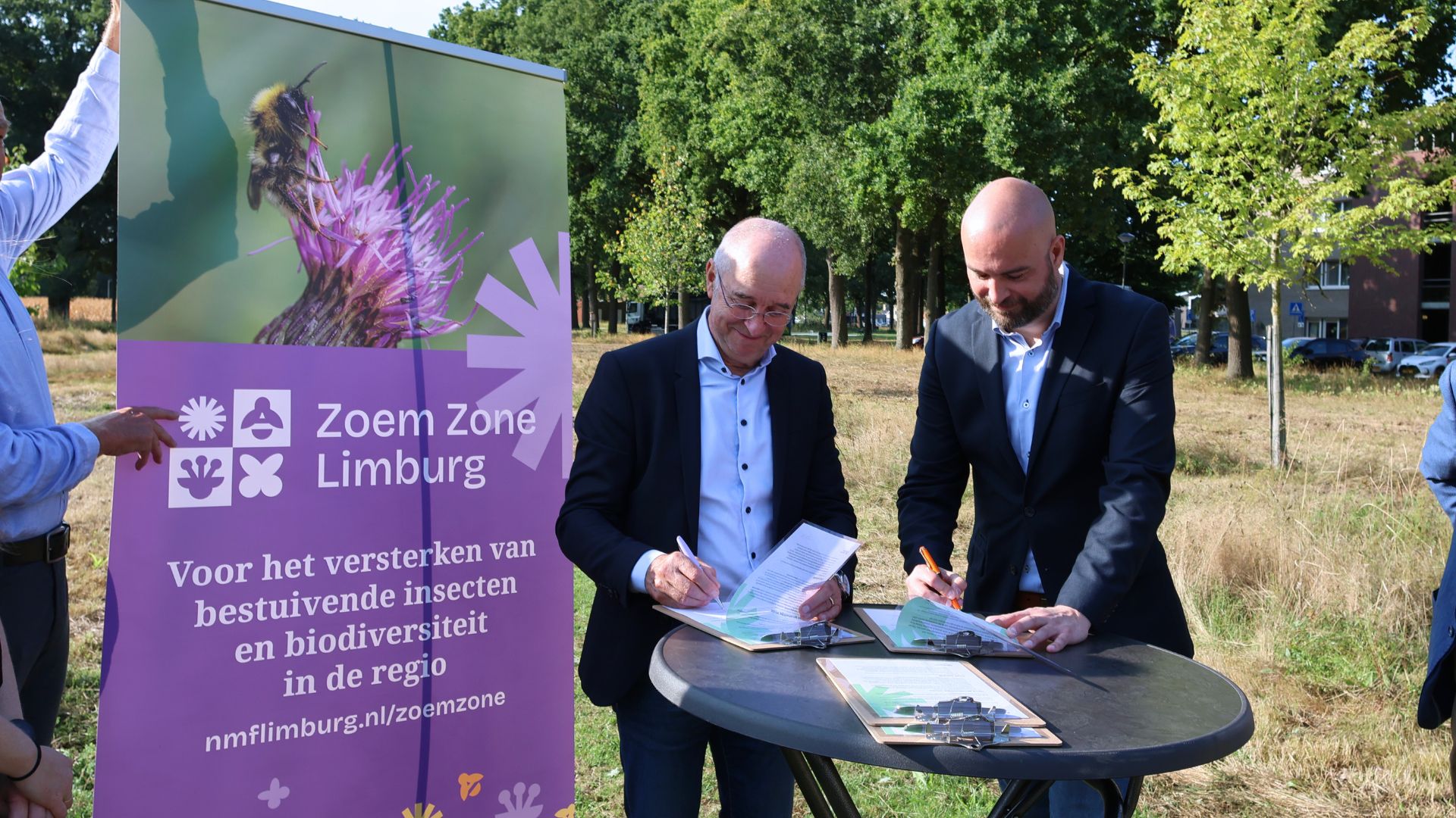 Harry Boesten en wethouder Blomen tekenen partnerschapsverklaring naast een banner van Zoem Zone Limburg