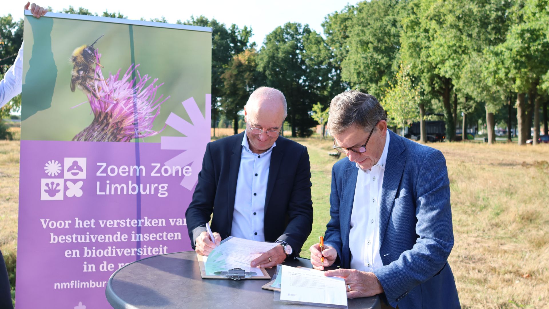 Harry Boesten en wethouder Meuwissen tekenen partnerschapsverklaring naast een banner van Zoem Zone Limburg