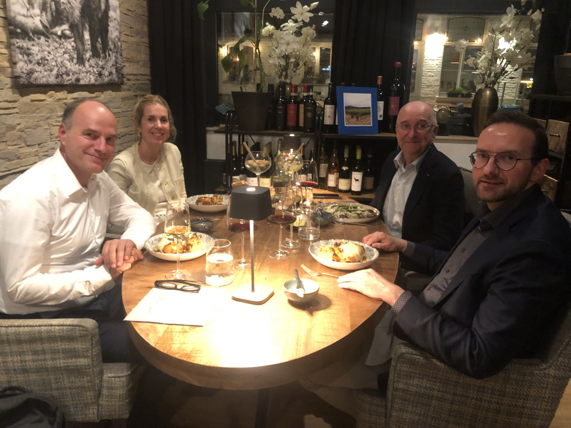Vier deelnemers van het gesprek zitten aan tafel.