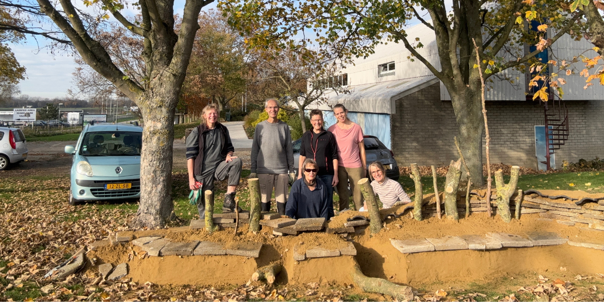 groep vrijwilligers staat achter net gemaakte bijenburcht
